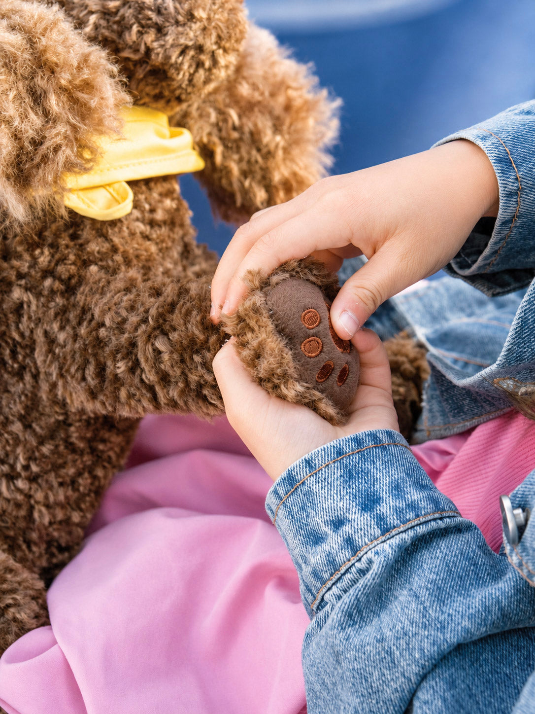 Hands holding Comfort Me Raffy’s embroidered paw